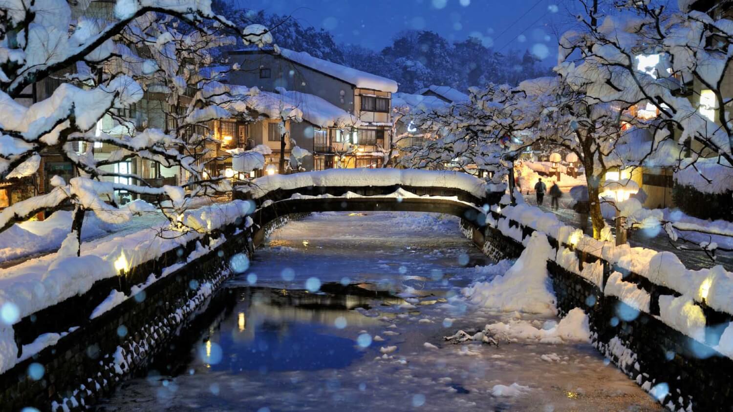 下雪的城崎溫泉，樹上、路邊都有厚厚的積雪，搭配溫泉老街與溪流，是令人難忘的景色